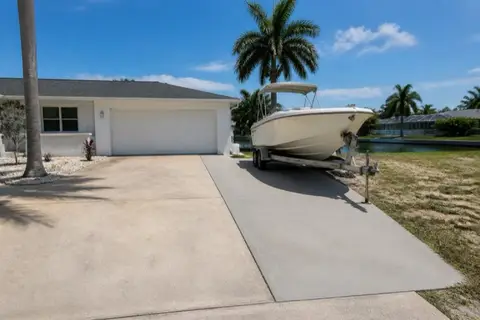 Cape Coral driveway widened with a newer concrete strip along one side, boat trailer parked on the fresh pour beside the older bleached slab